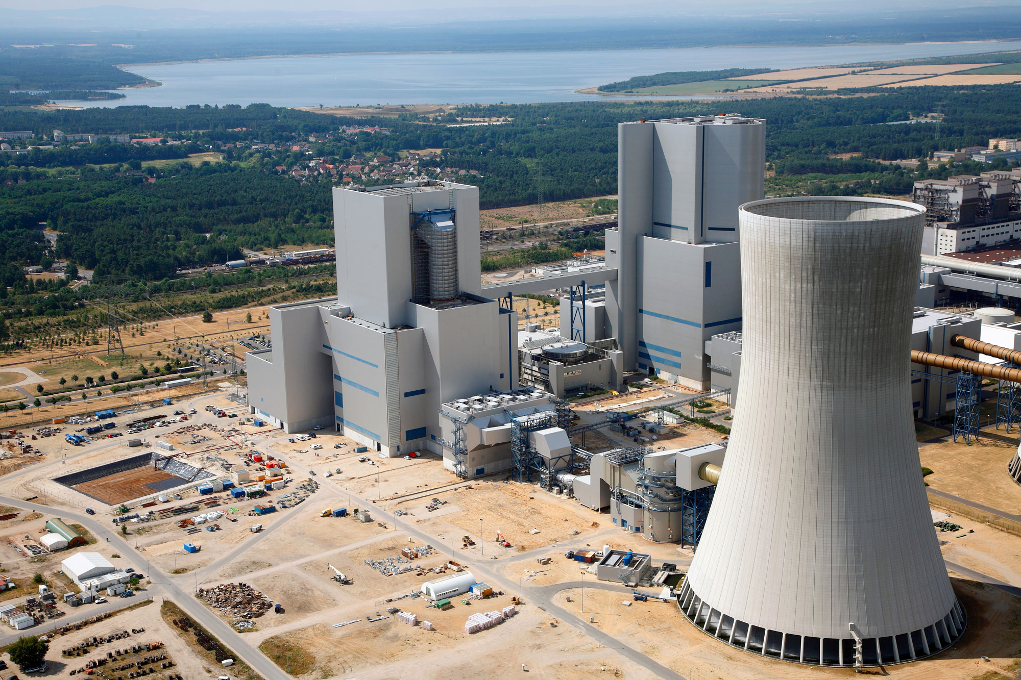 Luftaufnahme eines Kraftwerks mit Kühlturm und mehreren großen Gebäuden für die Energieerzeugung.