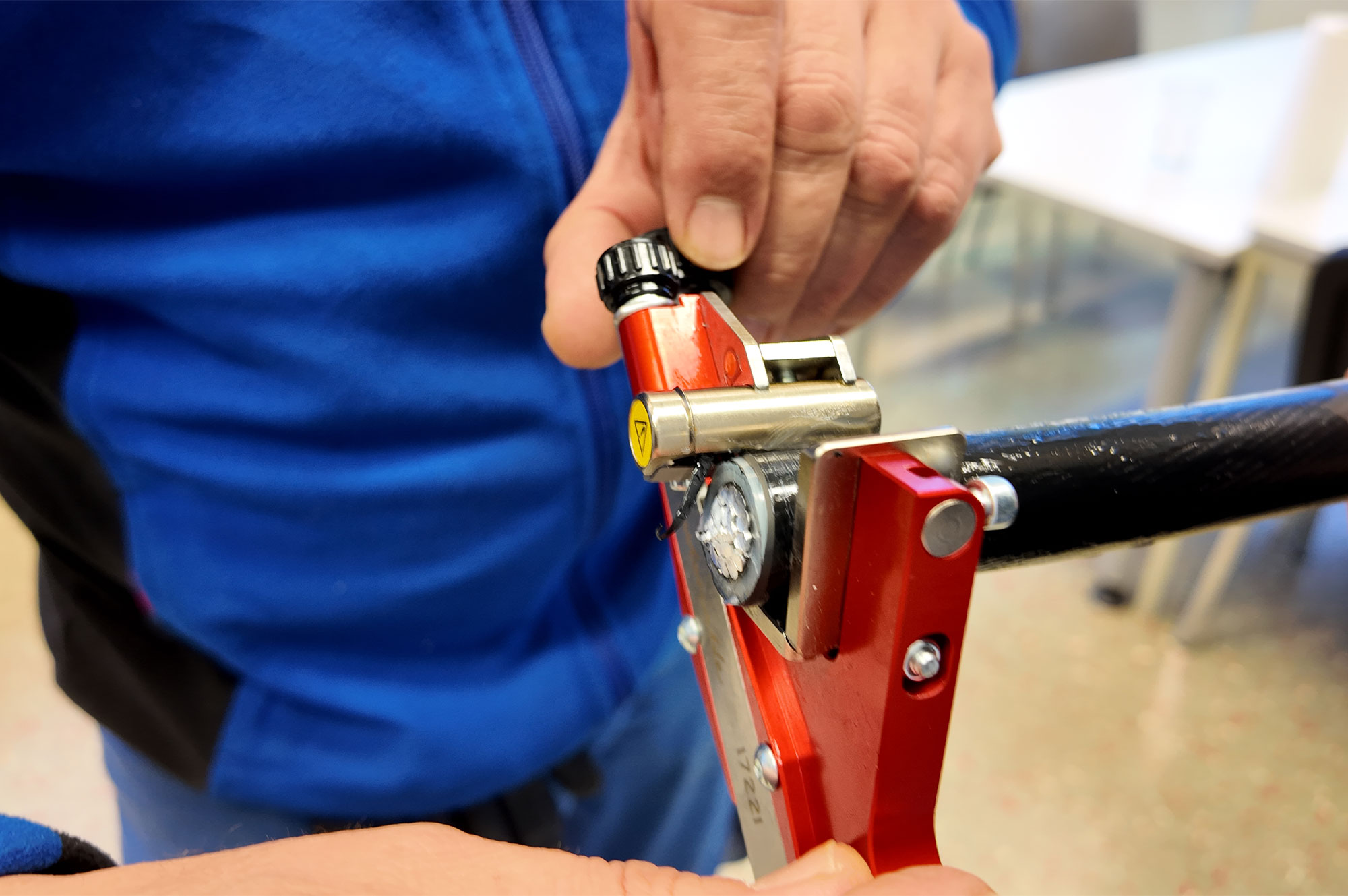 Nahaufnahme einer Person, die ein rotes Werkzeug mit einem Zifferblatt und einem Drehknopf in der Hand hält.
