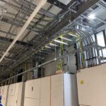 Technische Installation mit Kabelkanälen und Schaltschränken in einem modernen Gebäude. Sichtbare Verkabelung und elektrische Komponenten.