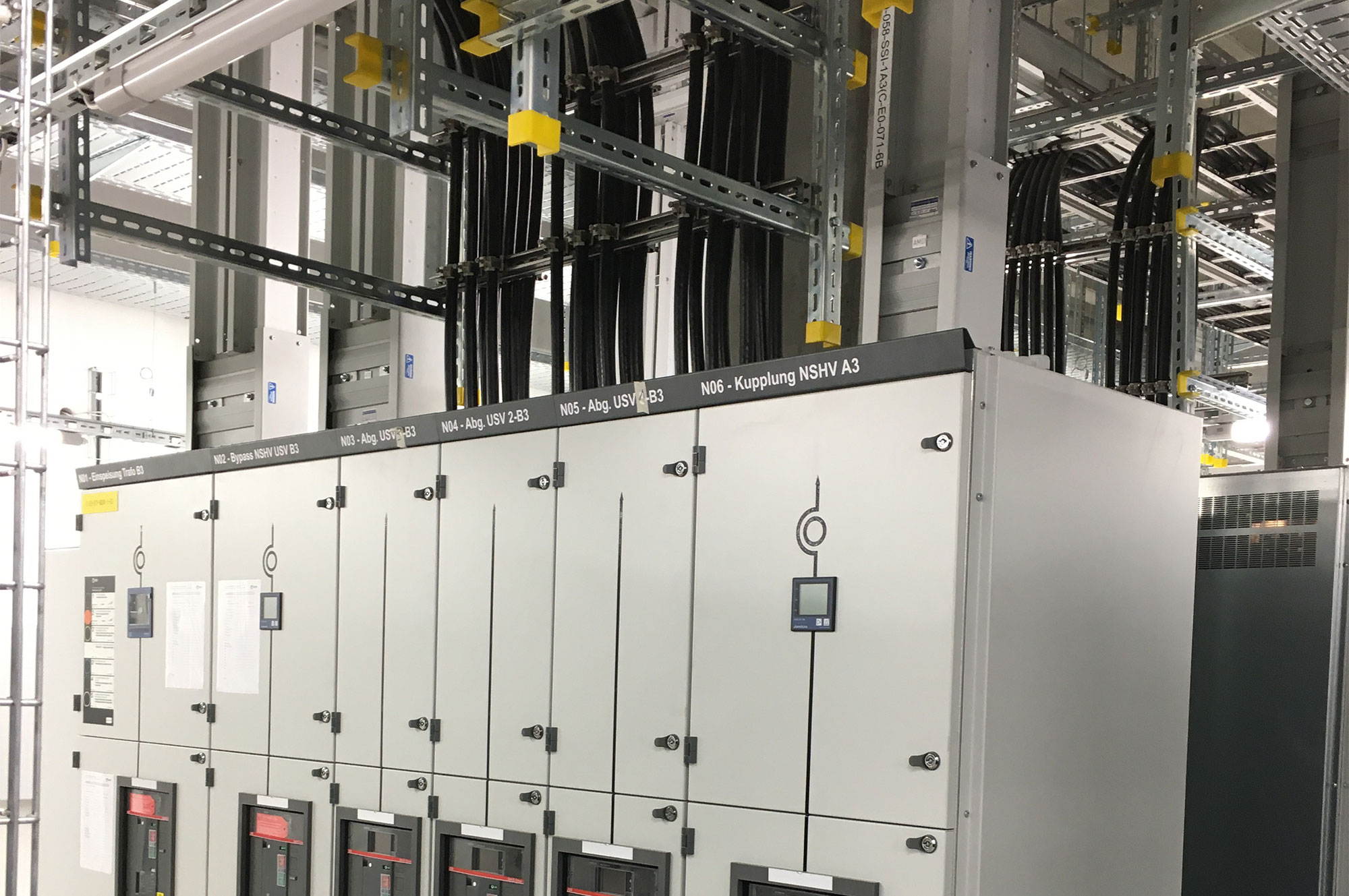 Verteilerkasten mit mehreren Schaltanlagen und Kabeln in einer technischen Umgebung.
