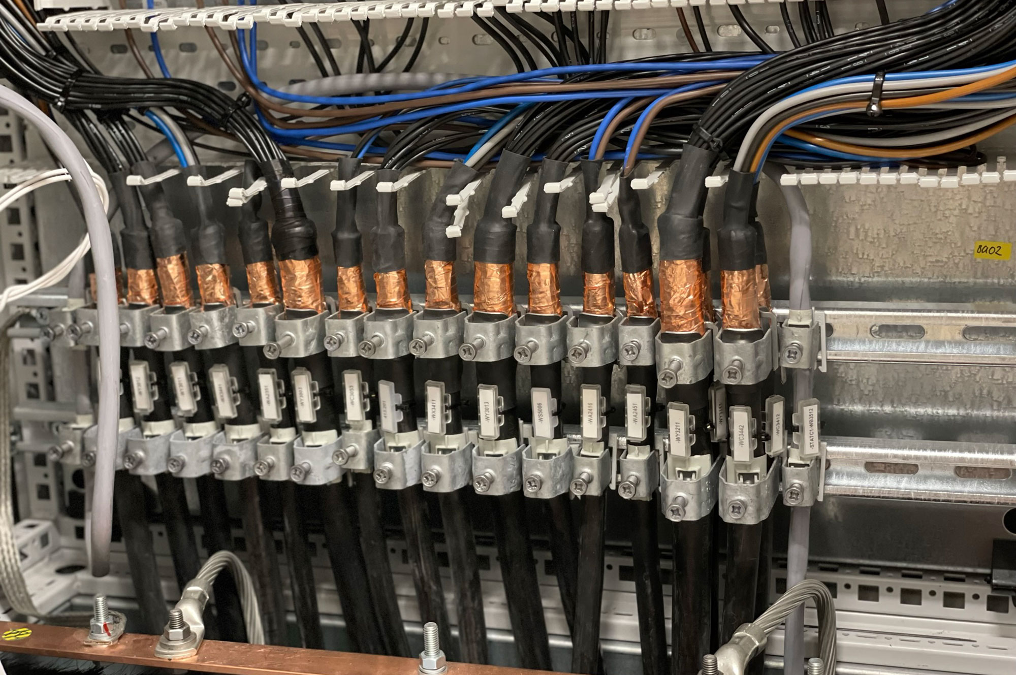 Anschlussarbeiten mit mehreren Kabeln und Kupferverbindungen in einem elektrischen Verteilerkasten.