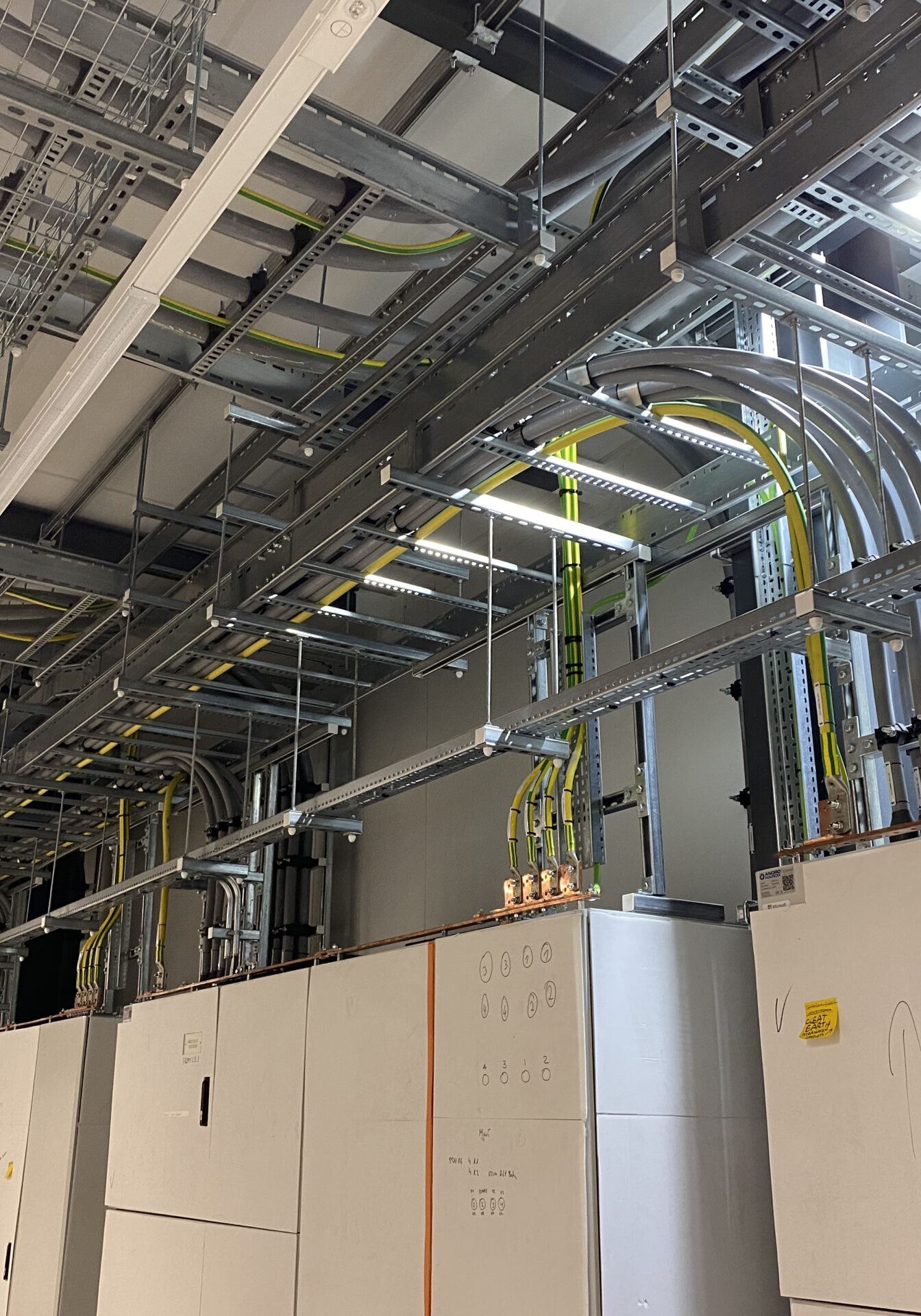 Technische Installation mit Kabelkanälen und Schaltschränken in einem modernen Gebäude. Sichtbare Verkabelung und elektrische Komponenten.
